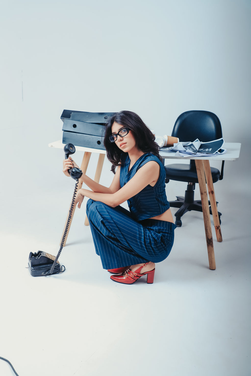 Woman in a blue outfit posing with a camera and equipment on a white background